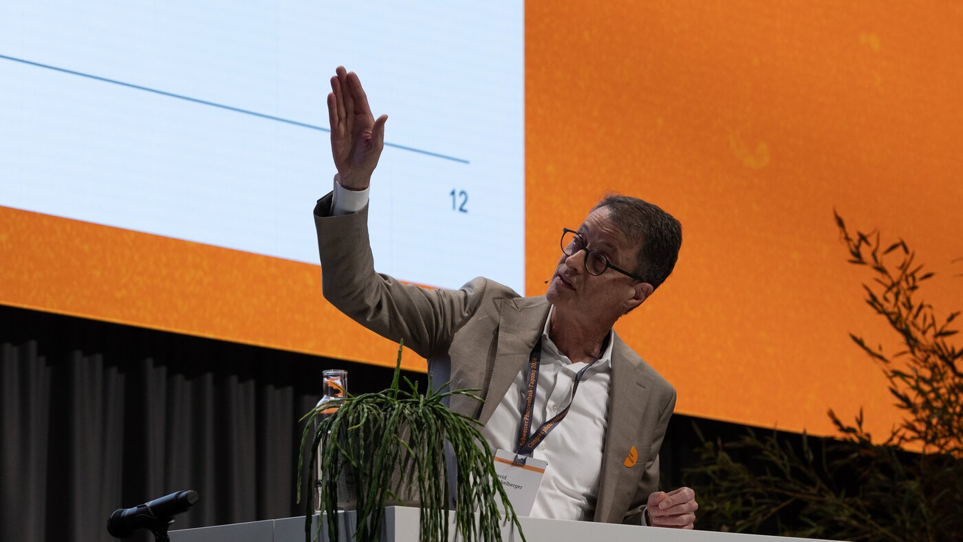 Mann mit braunem Jacket vor orangenem Hintergrund | © Swissolar / Sarah Bollmann