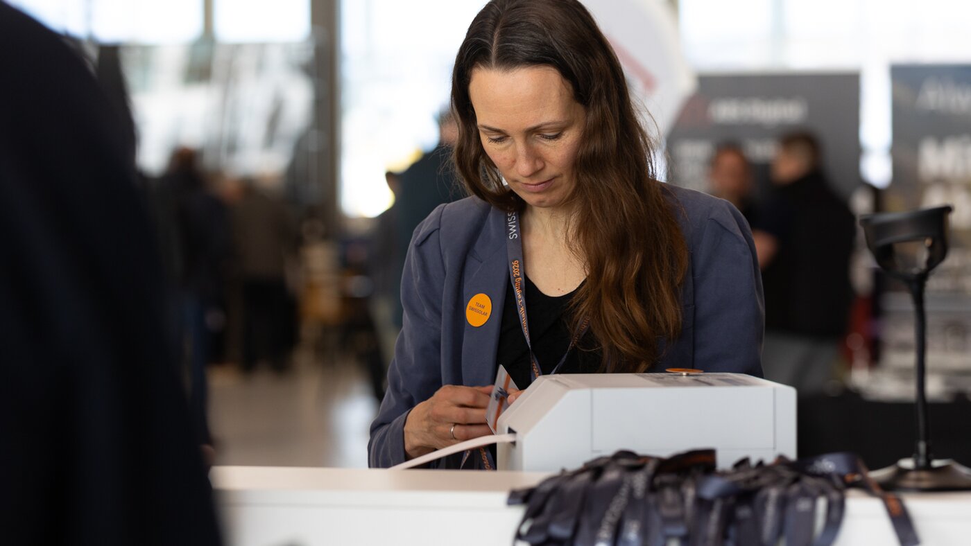 Frau mit blauen Jacket am Empfang  | © Swissolar / Sarah Bollmann