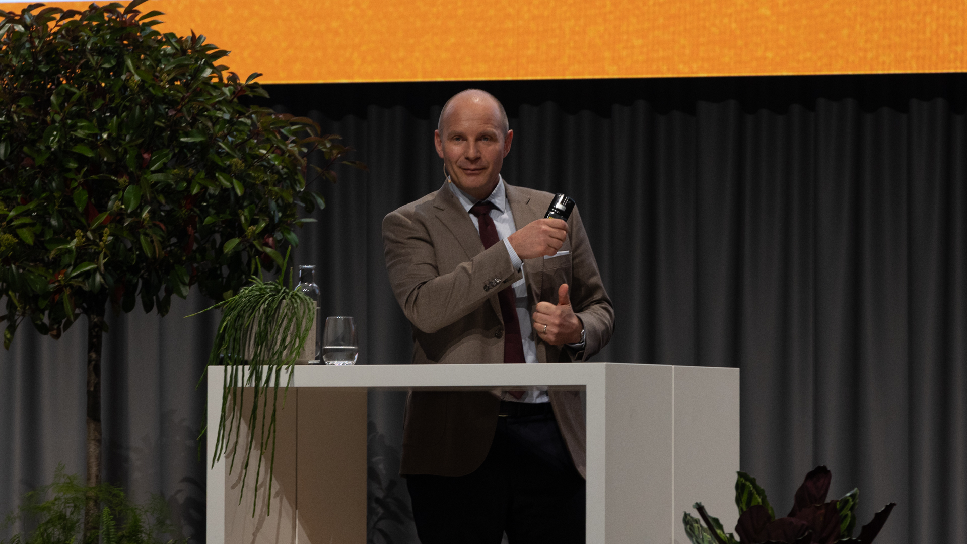 Mann mit braunem Jacket hinter weissen Stehtisch | © Swissolar / Sarah Bollmann, atelier olive GmbH