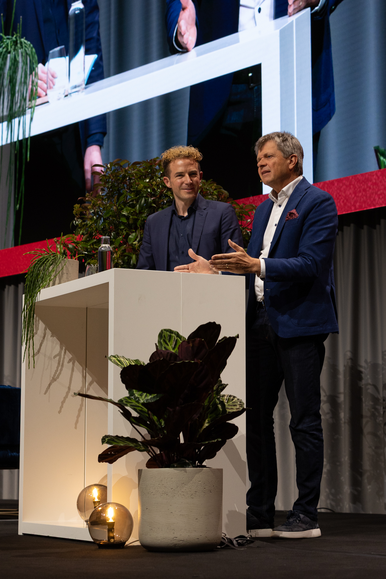 Zwei Männer auf einer Bühne stehend an weissen Tisch. | © Swissolar / Sarah Bollmann, atelier olive GmbH